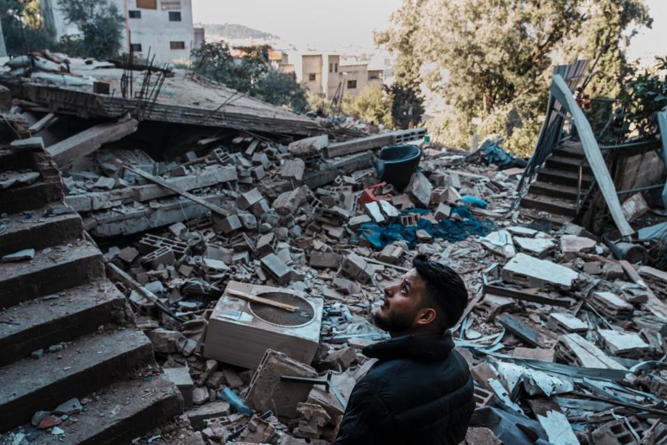 Ehab Maher Nafeer Mareei looks up to examine the remnants of his home after an Israeli airstrike destroyed it.