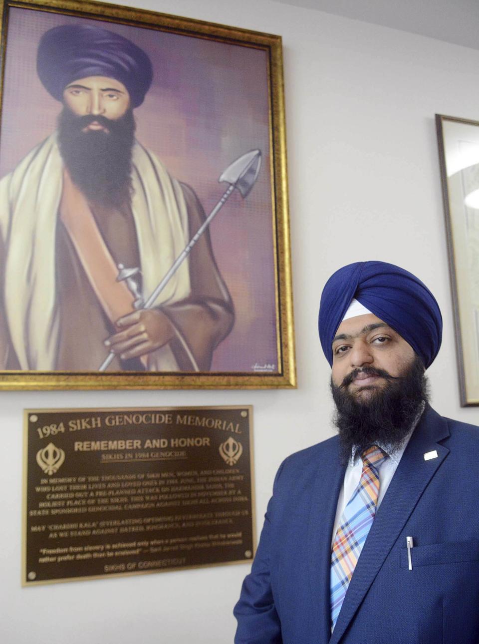 In this May, 29, 2019 photo, Swaranjit Singh Khalsa poses with the newly installed 1984 Sikh Genocide Memorial plaque at Otis Library in Norwich, Conn. The Connecticut library has removed the memorial to Sikhs killed in India 35 years ago after a protest call from the Indian Consulate in New York. (John Shishmanian/NorwichBulletin.com via AP)