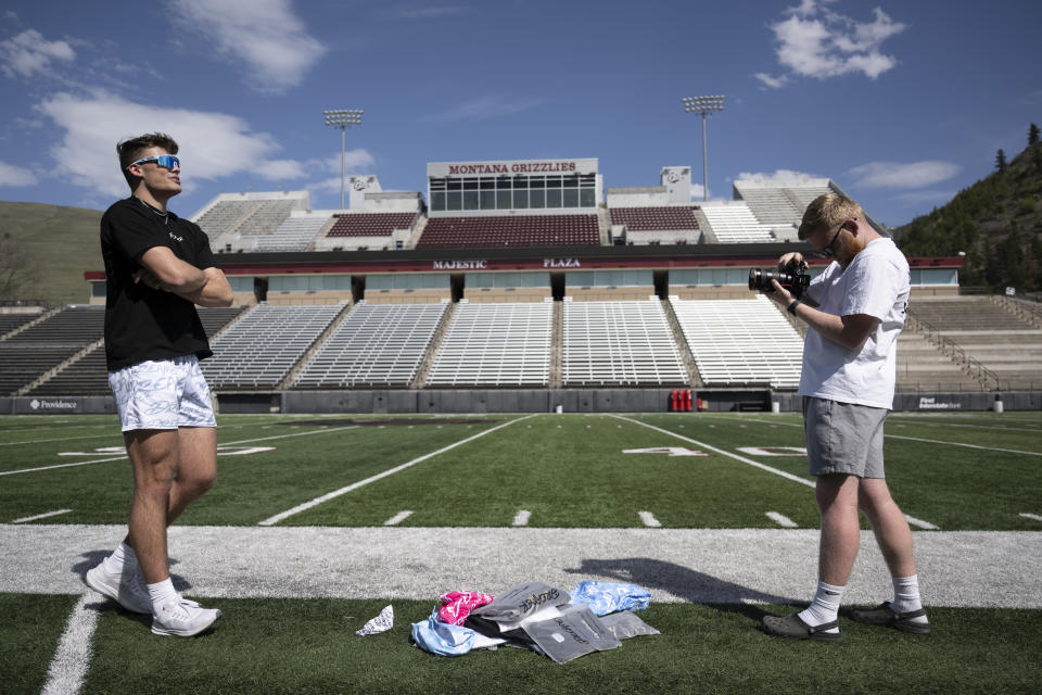 Adam Botkin, a football TikTok influencer, records a video for a post with Brandin Evans, right, at Washington-Grizzly Stadium in Missoula, Mont., on Monday, May 1, 2023. Botkin, a former walk-on place kicker and punter for the Montana Grizzlies, gained notoriety on the social media platform after videos of him performing kicking tricks went viral. (AP Photo/Tommy Martino)