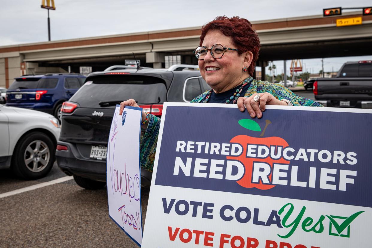 Nancy Vera, president of Corpus Christi American Federation of Teachers, stands on a busy traffic corner holding signs protesting against school vouchers and for Proposition 9 on Monday, Oct. 9, 2023, in Corpus Christi, Texas.