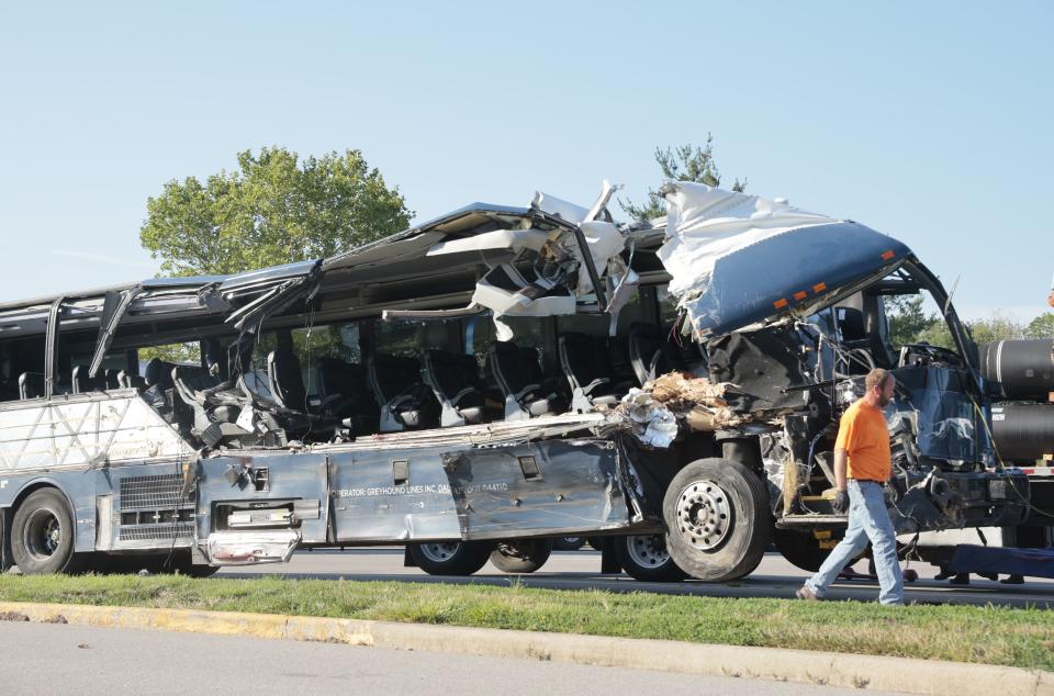 A worker helps clear the wreckage of a Greyhound bus that collided with tractor-trailers on the exit ramp to a rest area on westbound Interstate 70 in Highland, Ill., on Wednesday, July 12, 2023. (Christian Gooden/St. Louis Post-Dispatch via AP)
