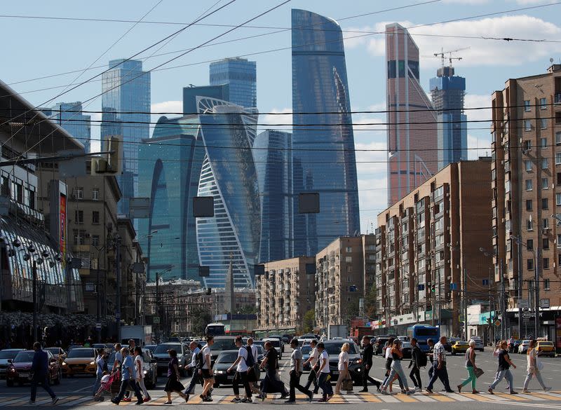 Pedestrians cross the road as skyscrapers of the Moscow International Business Center, also known as "Moskva-City", are seen in the background in Moscow