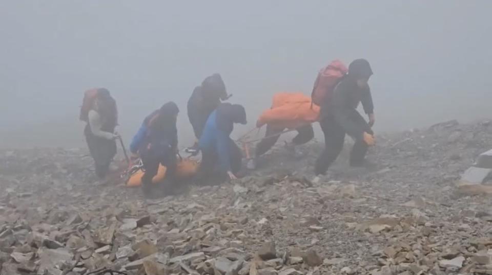 救難人員冒雨和大霧前往雪山翠池將罹難者搬運下山。（圖：苗栗消防局提供）