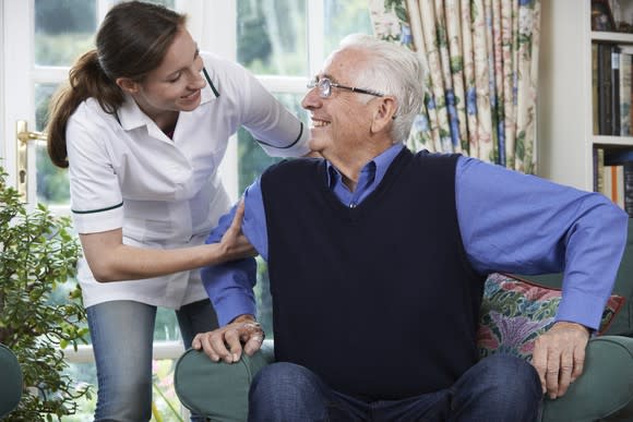 Woman helping senior male get out of a chair