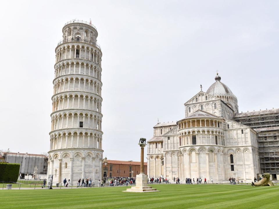 leaning tower of pisa white tower in green field with people gathered around the bottom