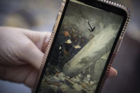 Lucía Ruiz, who survived an attack by the Basque separatist militant group ETA in 1987 when she was 10 years old, shows a photo of rescue efforts at the site of the blast that targeted the military police barracks where she lived with her father, a civil guard, in Zaragoza, Spain, Friday, Oct. 16, 2020. Josu Urrutikoetxea, the last known chief of ETA, the now-extinct Basque separatist militant group, goes on trial Monday Oct. 19, 2020 in Paris for terrorism charges that he deems “absurd” because of his role in ending a conflict that claimed hundreds of lives and terrorized Spain for half a century. (AP Photo/Renata Brito)