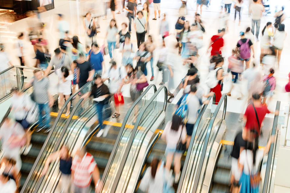 Shoppers going up and down a mall escalator.