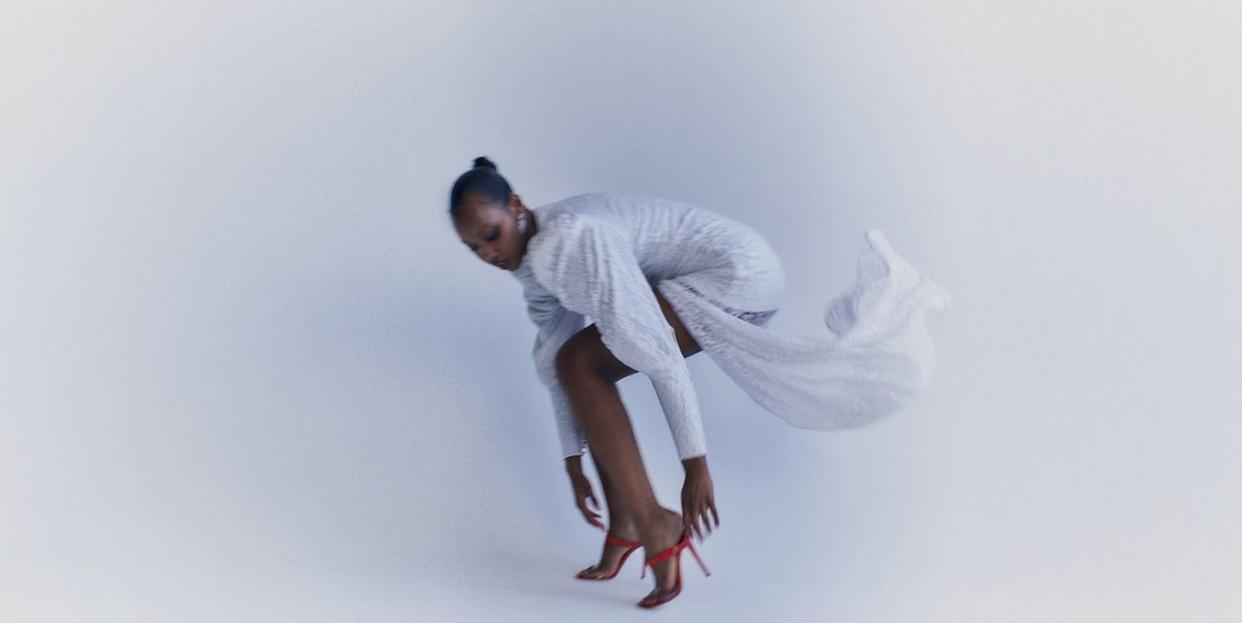 a black woman dressed in a sparkling gown with red shoes