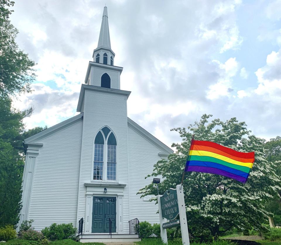 A pride flag hangs in front of a small Massachusetts church.