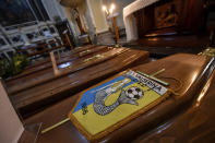 FILE - In this Saturday, March 21, 202 file photo, coffins, one of them with the pennant of the local soccer team, wait to be transported to cemetery, in the church of Serina, Seriana valley, where many Atalanta fans live, near Bergamo, Northern Italy. It was the biggest soccer game in Atalanta’s history and a third of Bergamo’s population made the short trip to Milan’s famed San Siro Stadium to witness it. Nearly 2,500 fans of visiting Spanish club Valencia also traveled to the Champions League match. More than a month later, experts are pointing to the Feb. 19 game as one of the biggest reasons why Bergamo has become one of the epicenters of the coronavirus pandemic — a “biological bomb” was the way one respiratory specialist put it — and why 35% of Valencia’s team became infected. The new coronavirus causes mild or moderate symptoms for most people, but for some, especially older adults and people with existing health problems, it can cause more severe illness or death. (Claudio Furlan/LaPresse via AP, File)