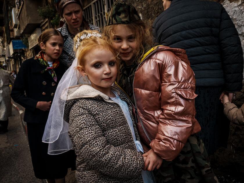 Paulina Hoffman, 6, and Teila Hoffman, 7, mingle with crowds on the streets at a Purim celebration.