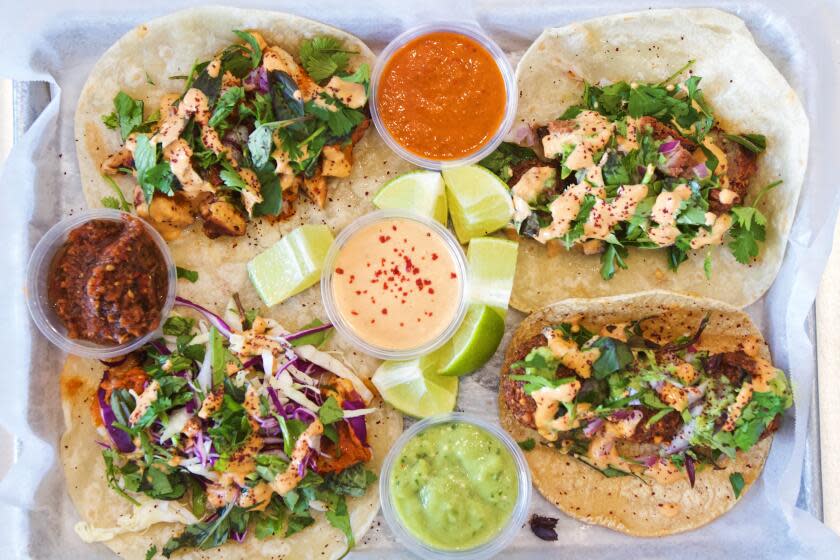 An overhead photo of a four-taco tray at Mid East Tacos in Silver Lake, sauces and lime wedges in the middle