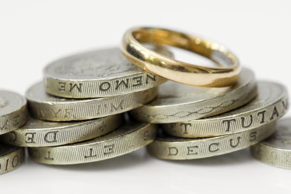 Gold wedding ring on top of pile of money