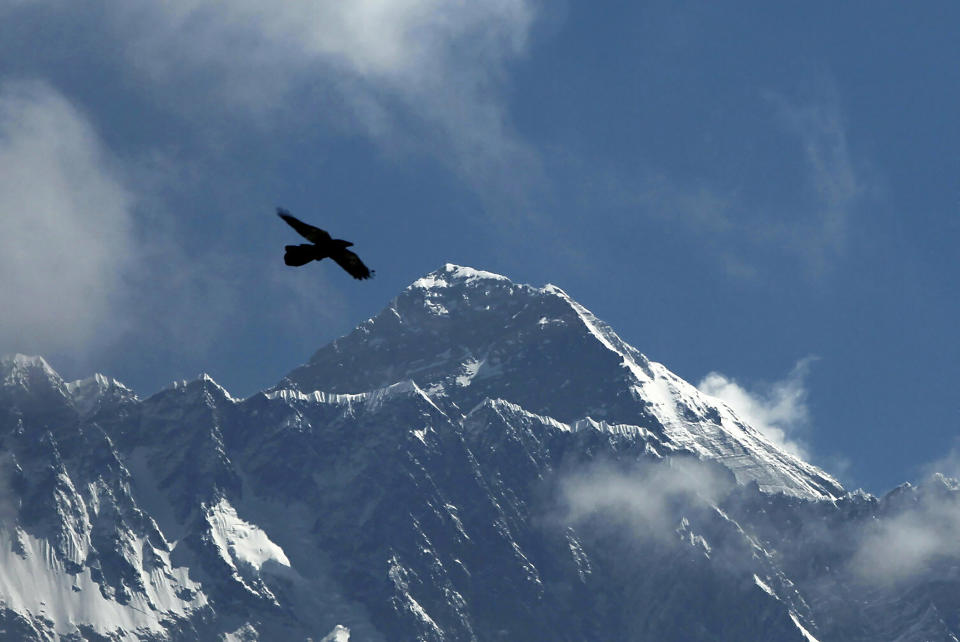 FILE - A bird flies with Mount Everest seen in the background from Namche Bajar, Solukhumbu district, Nepal, May 27, 2019. The race for the most successful ascents of Mount Everest is still on. Nepalese sherpa guide Pasang Dawa said on Thursday that he plans to climb the 8,849-meter (29,032-foot) peak next year in an attempt to match the record set by fellow Sherpa guide Kami Rita. (AP Photo/Niranjan Shrestha, File)