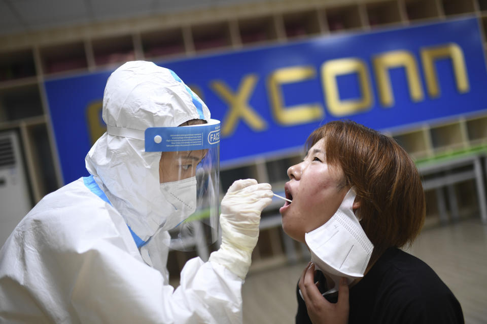 A medical worker takes a swab sample to test for COVID-19 from a worker at the Foxconn factory in Wuhan in central China's Hubei province Thursday, Aug. 5, 2021. China's "zero tolerance" strategy of quarantining every case and trying to block new infections from abroad helped to contain last year's outbreak and has kept China largely virus-free. But its impact on work and life for millions of people is prompting warnings that China needs to learn to control the virus without repeatedly shutting down the economy and society. (Chinatopix Via AP)