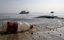 A plastic bottle and a tyre are seen near a fishing boat on Fundao beach in the Guanabara Bay in Rio de Janeiro March 13, 2014. According to the local media, the city of Rio de Janeiro continues to face criticism locally and abroad that the bodies of water it plans to use for competition in the 2016 Olympic Games are too polluted to host events. Untreated sewage and trash frequently find their way into the Atlantic waters of Copacabana Beach and Guanabara Bay - both future sites to events such as marathon swimming, sailing and triathlon events. REUTERS/Sergio Moraes (BRAZIL - Tags: ENVIRONMENT SPORT OLYMPICS)