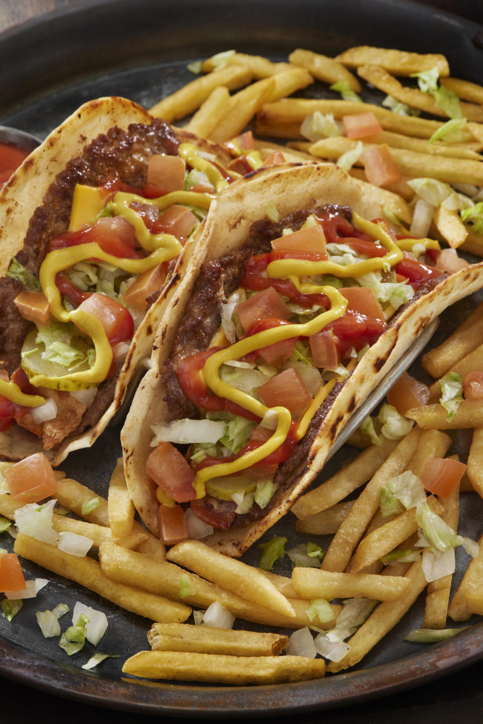 tacos dressed with ketchup and mustard served in a bed of fries