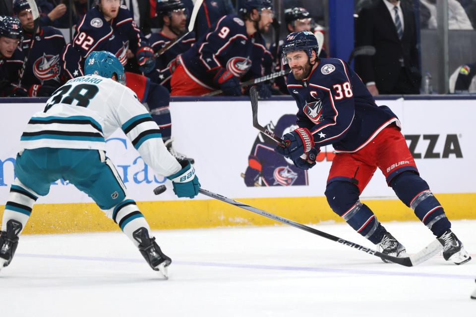 Columbus Blue Jackets forward Boone Jenner, right, passes the puck in front of San Jose Sharks defenseman Mario Ferraro during the second period of an NHL hockey game in Columbus, Ohio, Saturday, March 16, 2024. (AP Photo/Paul Vernon)