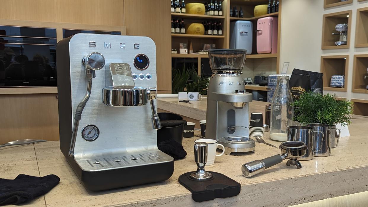  The EMC02 Mini Pro Espresso Coffee Machine on a countertop surrounded by coffee making accessories. 