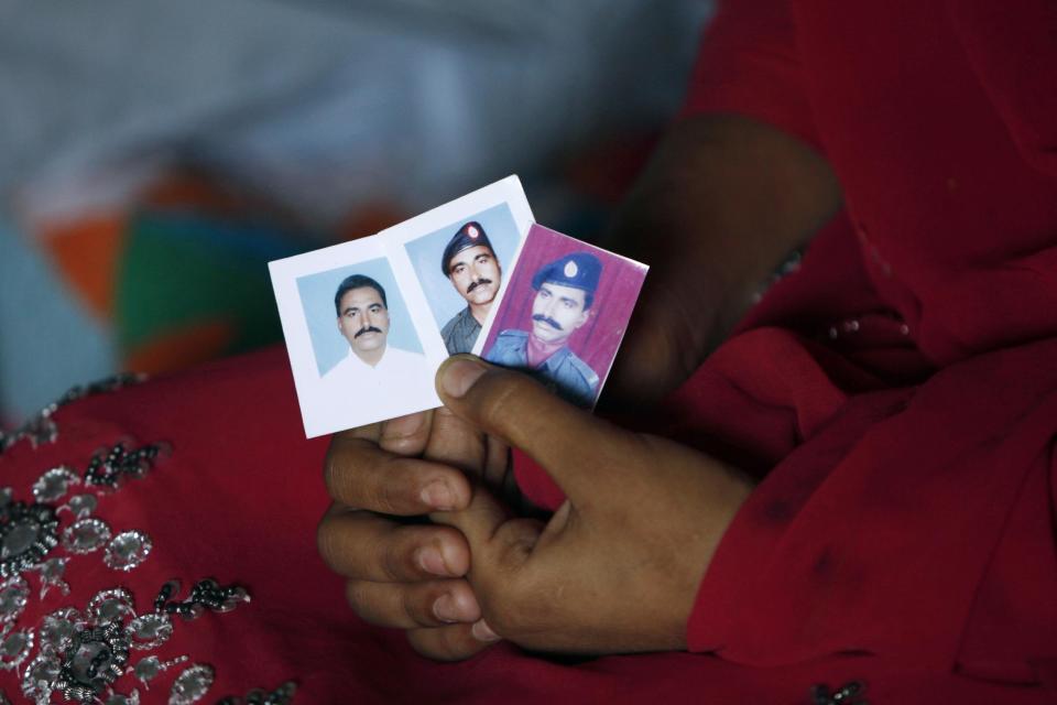 In this Wednesday, Feb. 26, 2014 photo, the daughter of Pakistani police officer Didar Ahmed, who was killed along with three other police officers in early February, displays his pictures, at her home in Karachi, Pakistan. The jacket that Karachi police officer Didar Ahmed was wearing when he was killed was given back to his family after his death. Bullet holes have pierced the sleeves and chest, marking where Ahmed was shot. In some areas the jacket is stained dark with dried blood. (AP Photo/Shakil Adil)