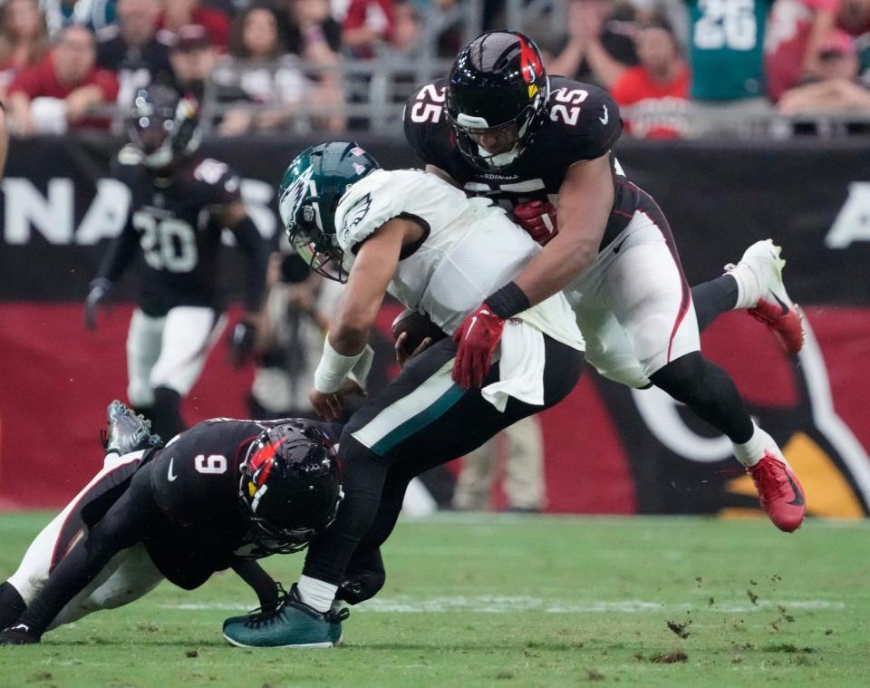 Philadelphia Eagles quarterback Jalen Hurts (1) is tackled by Arizona Cardinals linebackers Isaiah Simmons (9) and Zaven Collins (25) during the third quarter at State Farm Stadium in Glendale on Oct. 9, 2022.