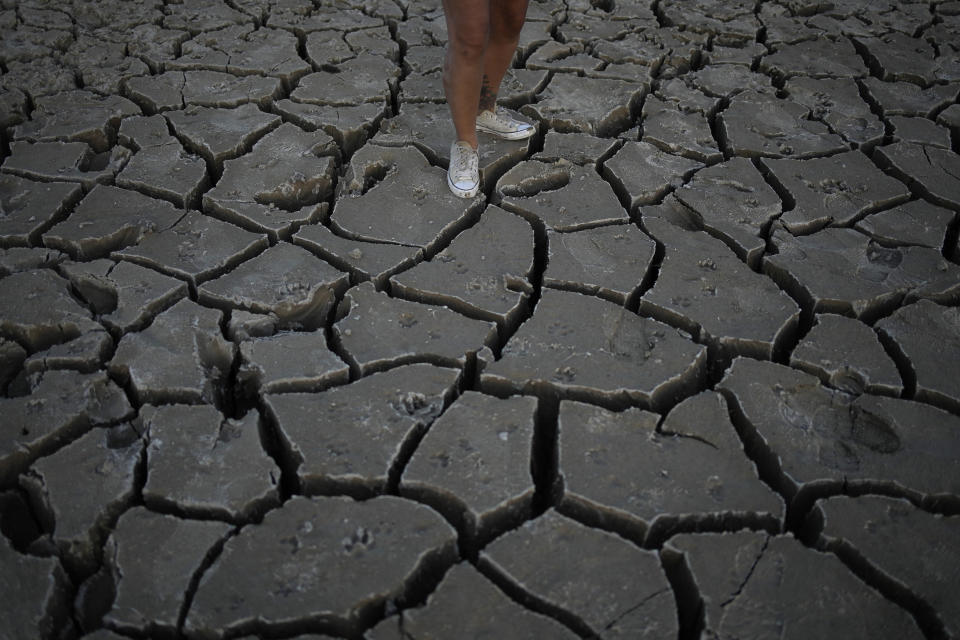 Misha McBride stands on cracked earth that was once underwater near Lake Mead at the Lake Mead National Recreation Area, Monday, May 9, 2022, near Boulder City, Nev. (AP Photo/John Locher)