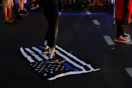 A protester stands on a "blue lives matter" flag after the not guilty verdict in the murder trial of Jason Stockley, a former St. Louis police officer, charged with the 2011 shooting of Anthony Lamar Smith, who was black, in St. Louis, Missouri, U.S., September 15, 2017. REUTERS/Whitney Curtis/