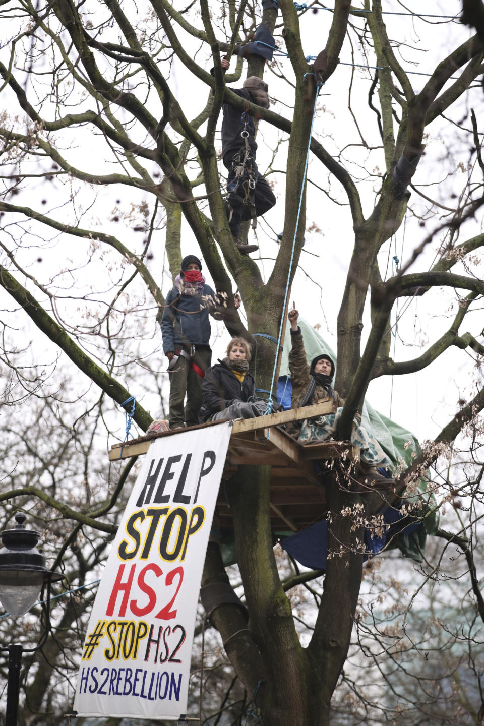 Protesters in trees at the encampment in Euston Square Gardens in central London, Wednesday Jan. 27, 2021. Protesters against a high-speed rail link between London and the north of England said Wednesday that some of them have been evicted from a park in the capital after they dug tunnels and set up a makeshift camp. (Aaron Chown/PA via AP)