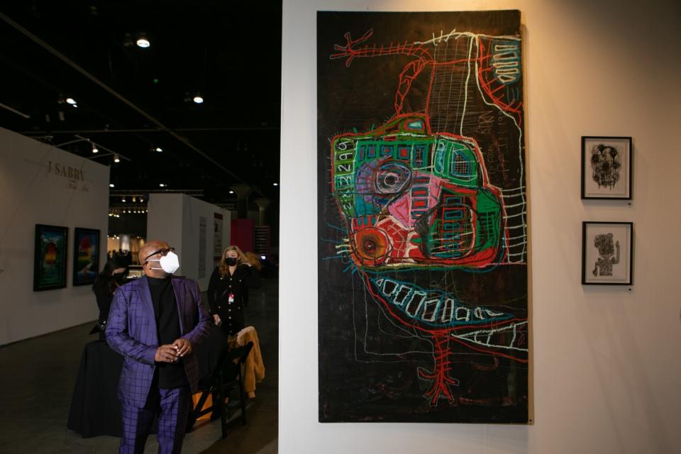 A man in a blue suit looks up at one of Tex Hammond's larger paintings.