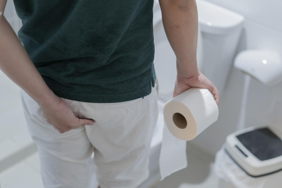 Man holding toilet paper roll in bathroom