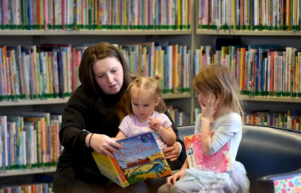 Stephanie King of Munroe Falls reads a story to daughters McKenna, 17 months, and Adelaide, 5, on a visit to North Canton Public Library.
