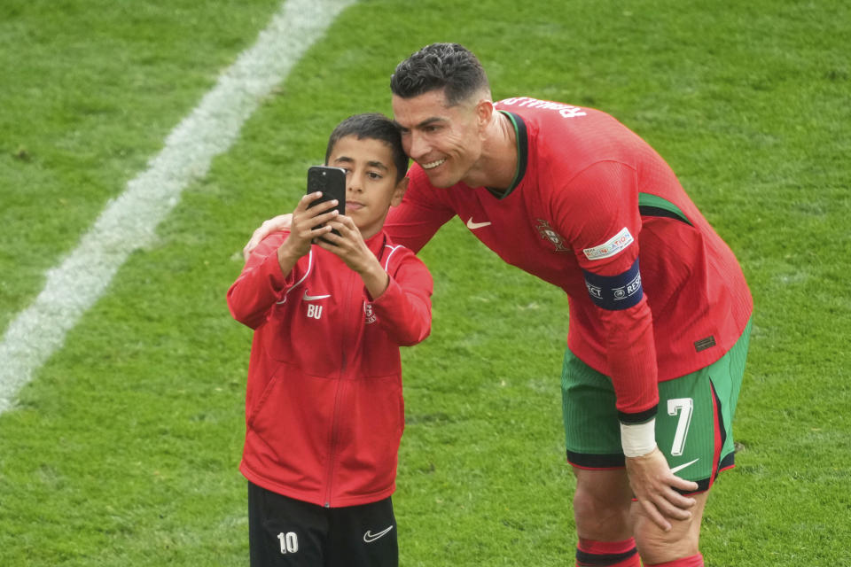 A young pitch invader takes a selfie with Portugal's Cristiano Ronaldo during a Group F match between Turkey and Portugal at the Euro 2024 soccer tournament in Dortmund, Germany, Saturday, June 22, 2024. (AP Photo/Michael Probst)