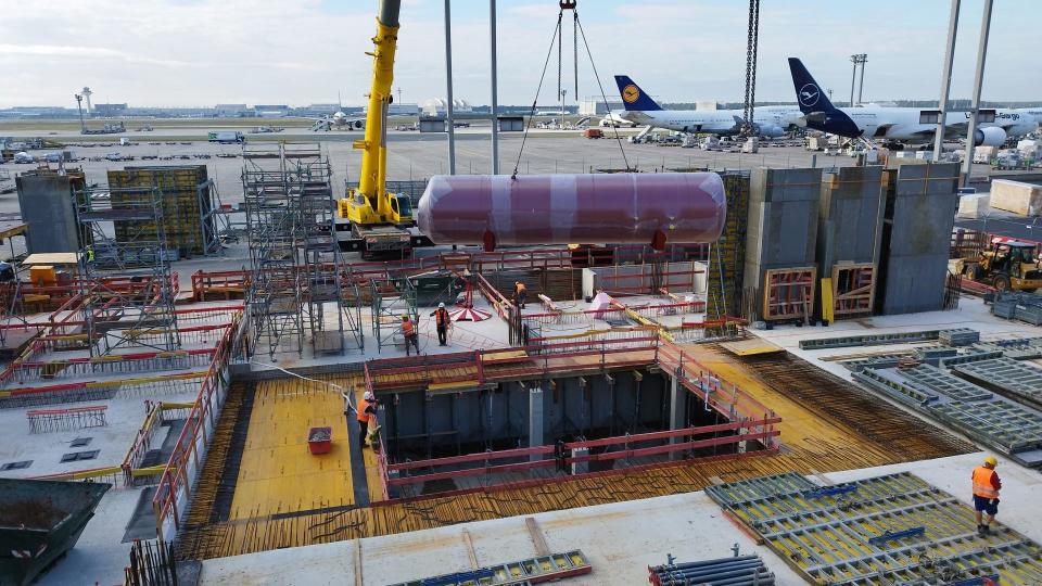 Construction work on a warehouse at the airport, with planes in the background.