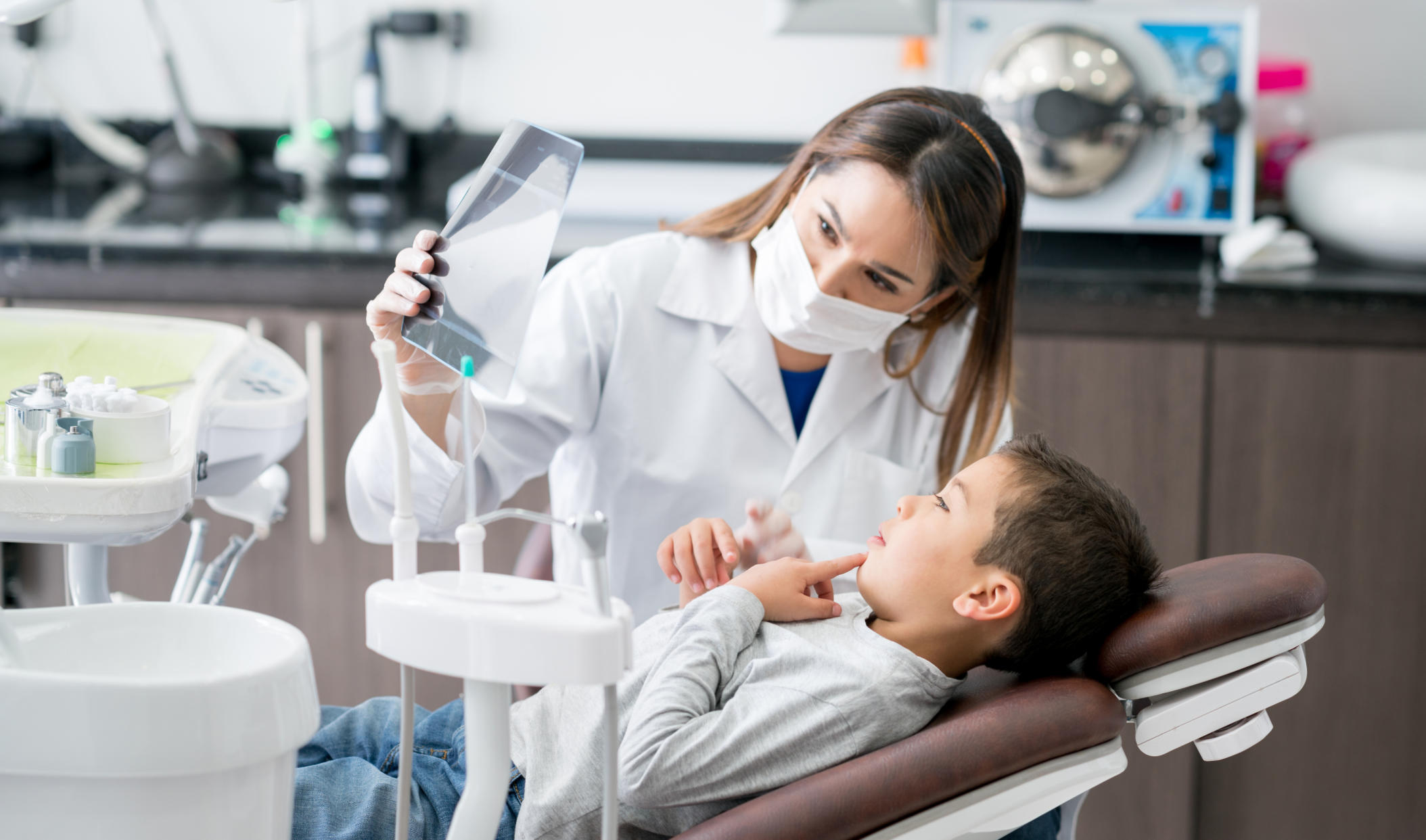 Happy dentist looking at an x-ray with his young patient at the office - healthcare and medicine concepts