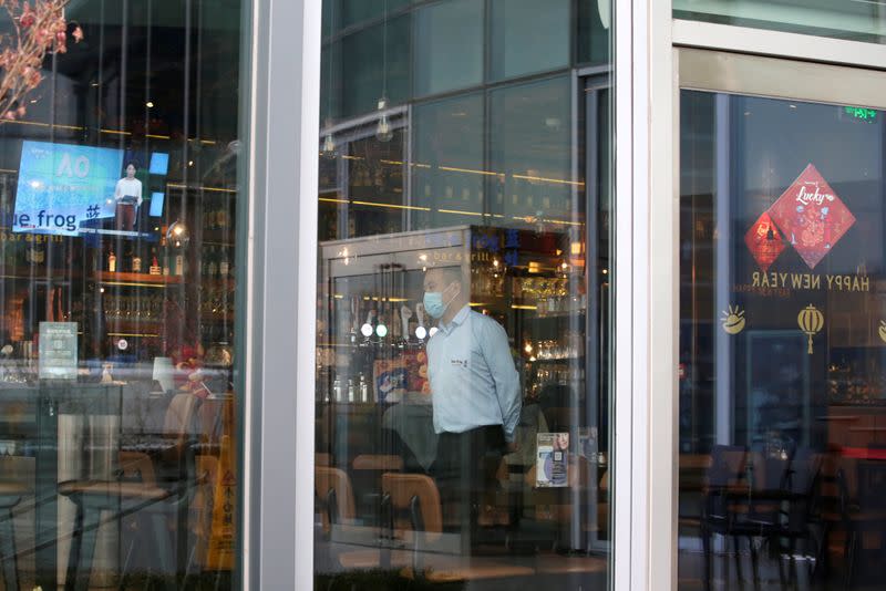 Employee wearing a mask is seen at a restaurant without guests in Beijing's central business area