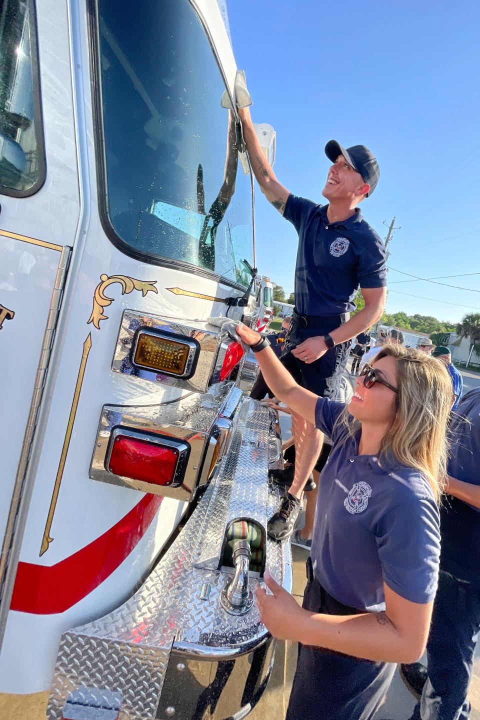 Ocean City-Wright Fire Control District Engineer Hannah Robertson and Firefighter/Paramedic Donovan Robertson wipe down the department's new fire engine during a ceremony Tuesday evening at the Racetrack Road station.
