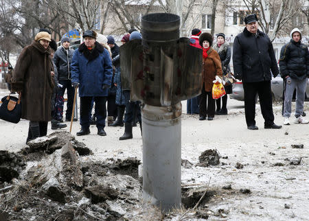 People look at the remains of a rocket shell on a street in the town of Kramatorsk, eastern Ukraine February 10, 2015. REUTERS/Gleb Garanich