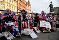 <p>Estas personas esperan sentadas en el suelo con banderas a la boda del próximo sábado en las cercanías del Castillo de Windsor. (Foto: Toby Melville / Reuters). </p>