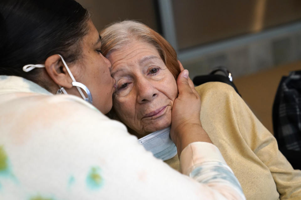 FILE - Rosa DeSoto, left, embraces her 93-year-old mother Gloria DeSoto, who suffers from dementia, inside the Hebrew Home at Riverdale, Sunday, March 28, 2021, in the Bronx borough of New York. It was the first time in over a year that residents' families were allowed to enter the nursing home for in-person visits allowing physical contact among loved ones. A focus on the elderly at the start of the nation's vaccination campaign helped protect nursing homes that were ravaged at the height of the U.S. coronavirus outbreak, but they are far from in the clear. New outbreaks, often traced to infected staff members, are still occurring in long-term care centers across the country, causing continued havoc for visitation policies. (AP Photo/Kathy Willens)