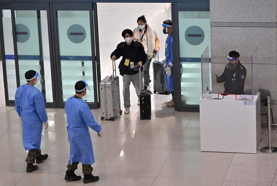 Health workers guide travellers arriving from China to a COVID-19 testing center at Incheon International Airport, west of Seoul, January 3, 2023. / Credit: JUNG YEON-JE/AFP/Getty