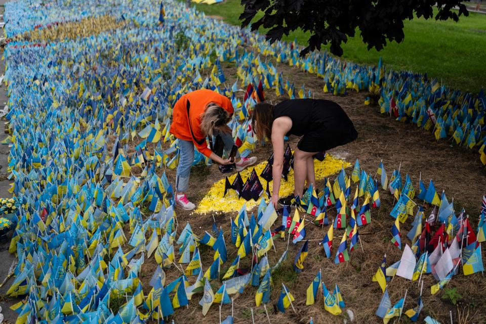 Tetiana Poltorak, left, and Tetiana Artemenko place flags to honor Ukrainian prisoners of war killed in the Olenivka region at a memorial site near the Independence Square in Kyiv on July 5, 2023.