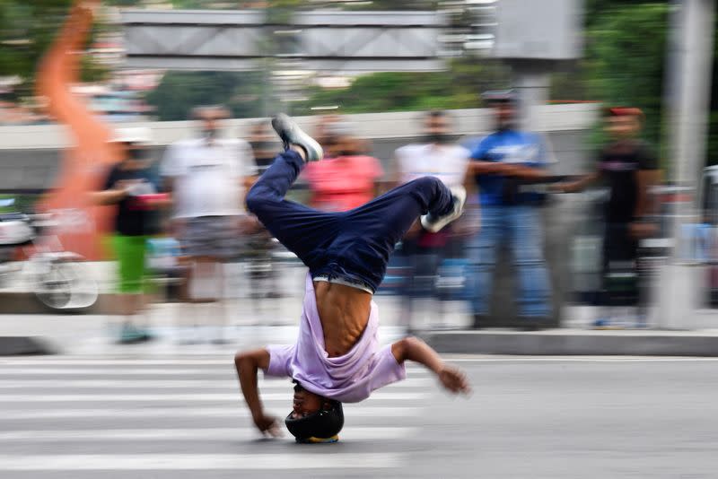 El atleta profesional de breakdance venezolano Kenyer Méndez, de 27 años, se desliza por una calle de cabeza en un semáforo, en Caracas