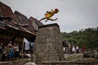 NIAS ISLAND, INDONESIA - FEBRUARY 24: A villager wearing traditional costume jumps over a stone in front of their ancient houses in Orahili Fau village on February 24, 2013 in Nias Island, Indonesia. Stone Jumping is a traditional ritual, with locals leaping over large stone towers, which in the past resulted in serious injury and death. Stone jumping in Nias Island was originally a tradition born of the habit of inter tribal fighting on the island of Nias. (Photo by Ulet Ifansasti/Getty Images)