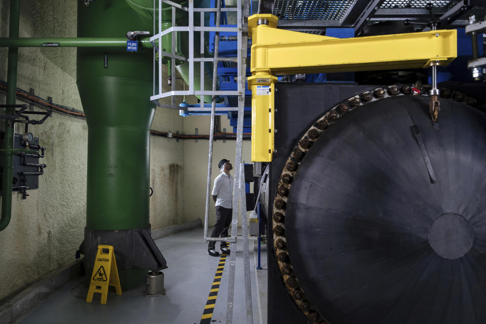 A worker inspects machines at part of Fraicheur de Paris' underground cooling system, in Paris, Tuesday, July 26, 2022. The system, which uses electricity generated by renewable sources, is the largest in Europe and goes unnoticed above ground. (AP Photo/Lewis Joly)