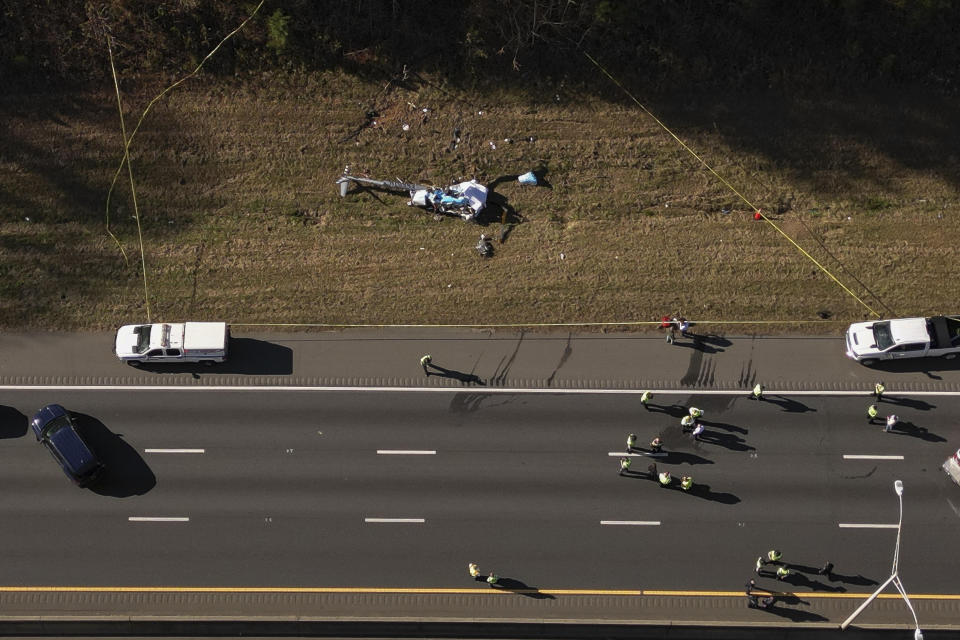 In this image take with a drone, emergency personnel work at the scene of a helicopter crash on the side of Interstate 77 South in Charlotte, N.C., Tuesday, Nov. 22, 2022. Authorities said two people died. ( (Alex Slitz/The Charlotte Observer via AP)