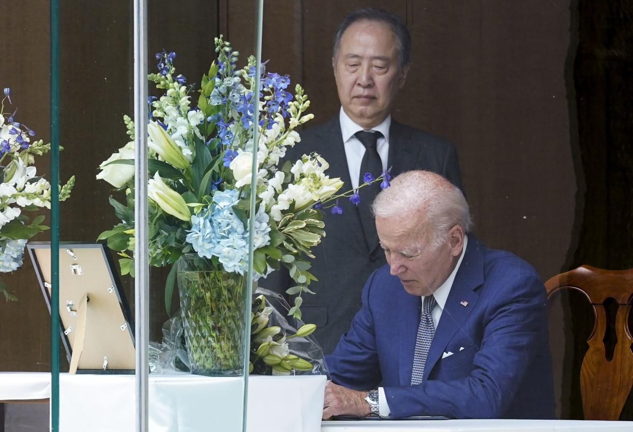 President Joe Biden signs a condolence book at the Japanese ambassador's residence in Washington, Friday, July 8, 2022, for former Japanese Prime Minister Shinzo Abe who was assassinated on Friday while campaigning. Japanese Ambassador to the United States Koji Tomita looks on. 
