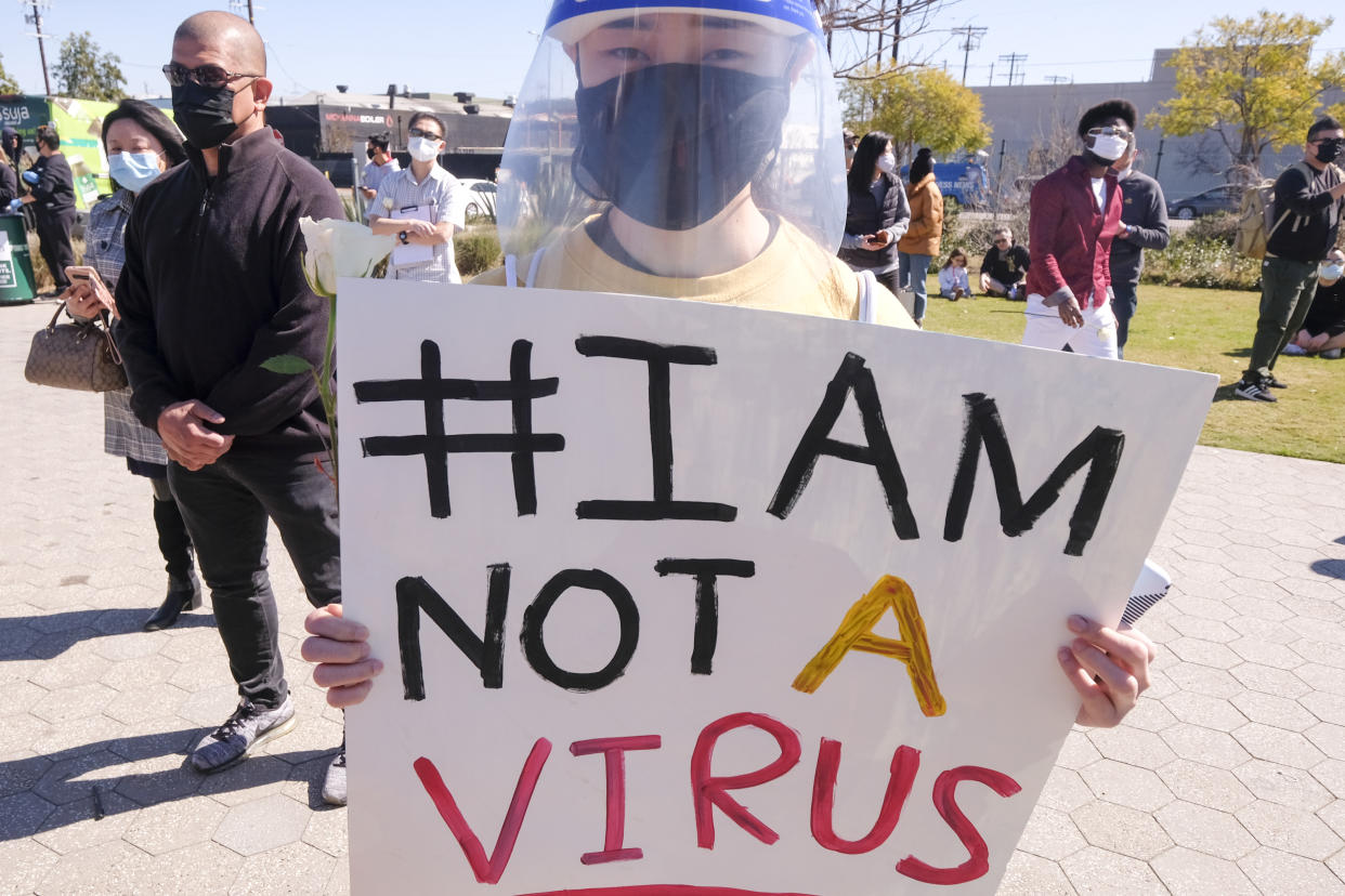 TOPSHOT - Tracy Wong wearing a face mask and holding a sign takes part in a rally to raise awareness of anti-Asian violence, near Chinatown in Los Angeles, California, on February 20, 2021. - The rally was organized in part in response to last month's fatal assault of Vicha Ratanapakdee, an 84-year-old immigrant from Thailand, in San Francisco. (Photo by RINGO CHIU / AFP) (Photo by RINGO CHIU/AFP via Getty Images)