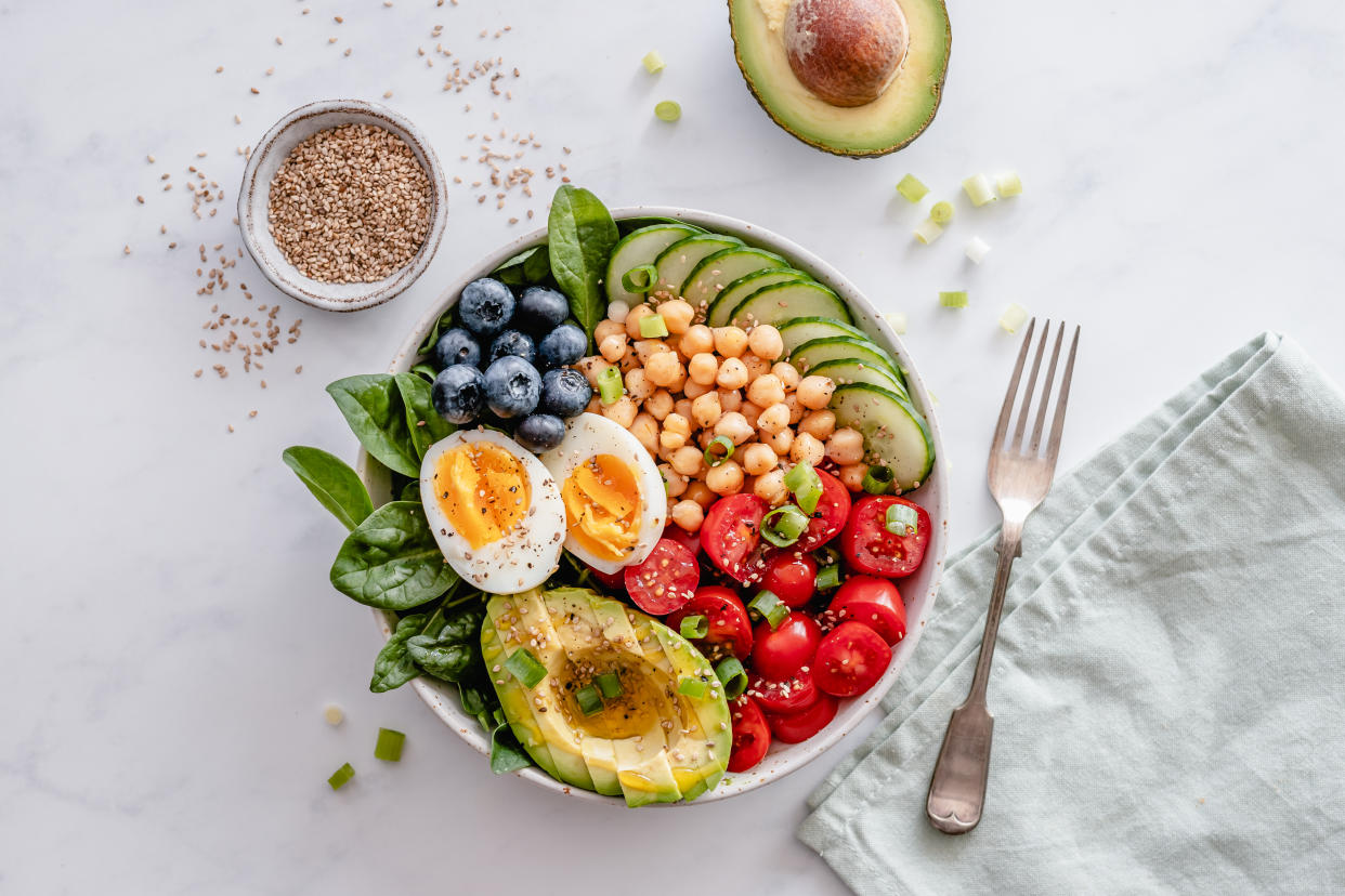 A salad bowl with eggs, avocado, chickpeas, blueberries, cucumber and tomatoes