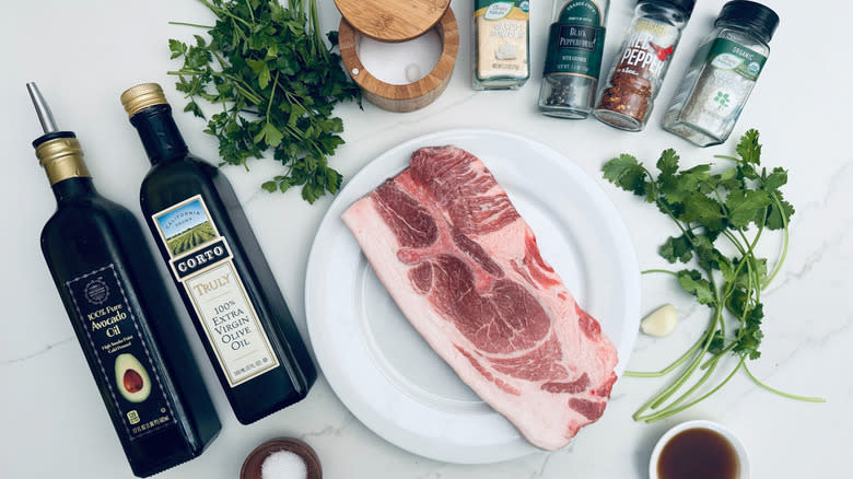 chimichurri ingredients and pork steak on marble counter