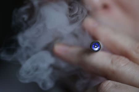 A man uses an E-cigarette, an electronic substitute in the form of a rod, slightly longer than a normal cigarette, in this March 5, 2013 file illustration picture taken in Paris. REUTERS/Christian Hartmann/Files